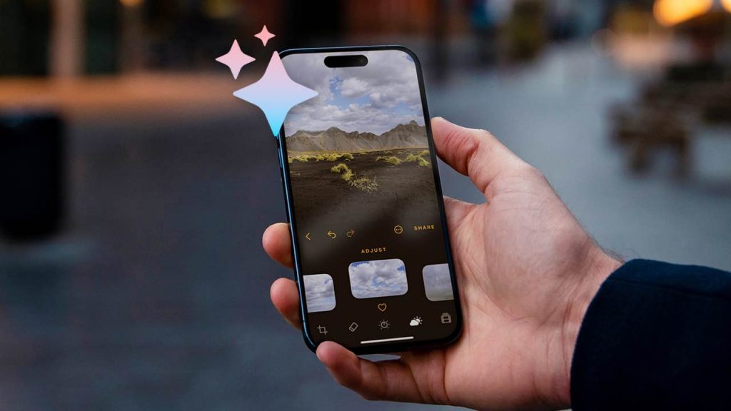 Mano sosteniendo un smartphone mostrando la interfaz de una aplicación de edición de fotos con IA, con varias opciones de ajuste y una imagen de un paisaje en la pantalla principal.